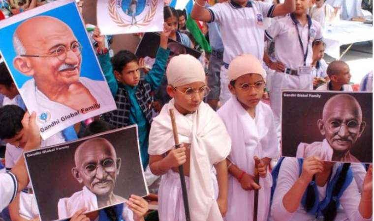 Students and citizens celebrating Gandhi Jayanti with lamps and flowers