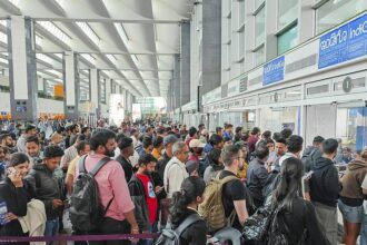 Passengers waiting in long queues at an Indian airport due to IndiGo flight delays and cancellations.