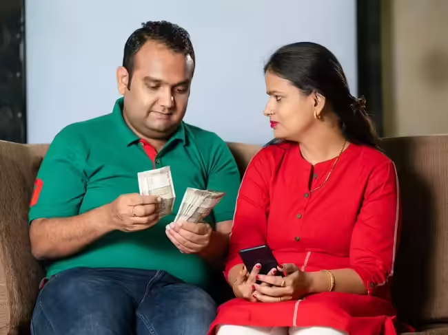 Indian couple planning budget and financial goals using notebook and calculator